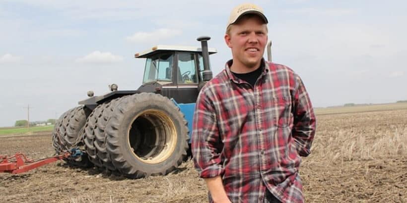 FarmerTractor_Bannersnack Farmer standing in front of a tractor in a field