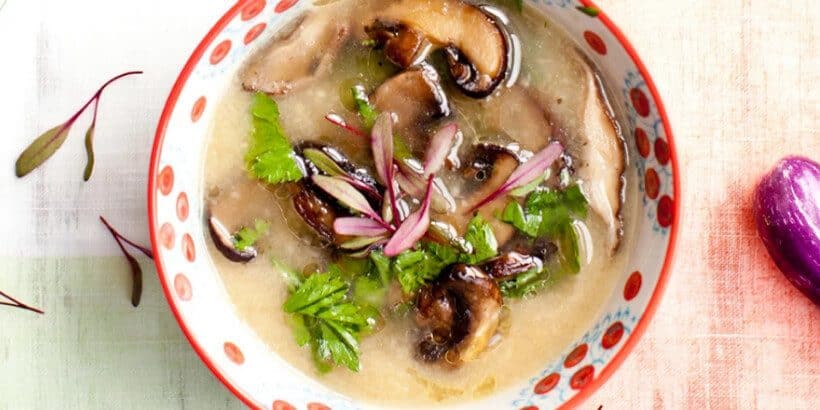 HealYourGutCoverImage Bowl of soup with mushrooms and herbs on a table