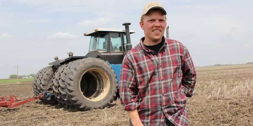 FarmerTractor_Bannersnack Farmer standing in front of a tractor in a field
